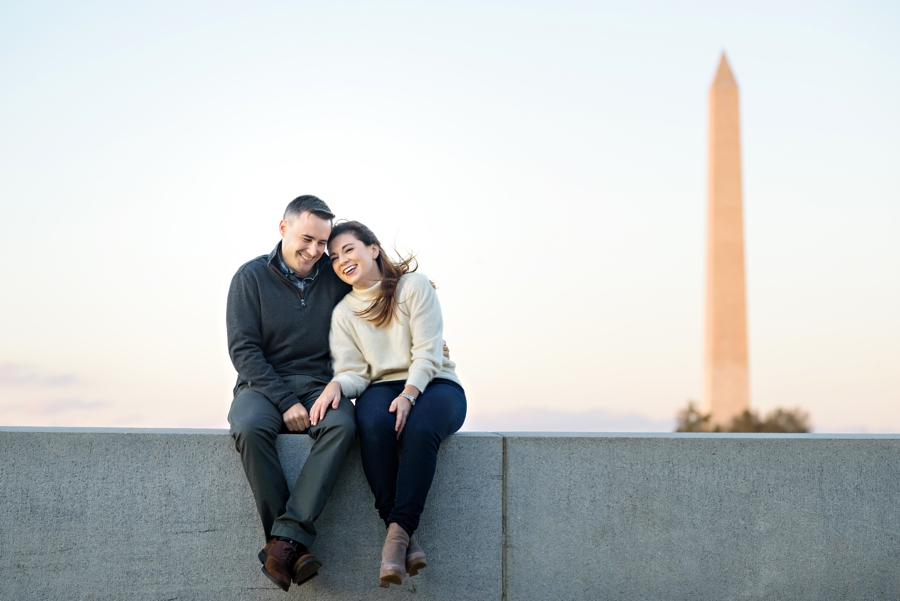 A couple holding hands and talking with the washington monument behind them.